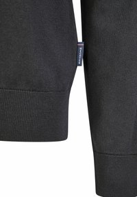 Zwarte gebreide trui met mouw, featuring een geribbelde manchette en een logosticker in het blauw met witte letters. Gezien vanuit een close-up hoek.