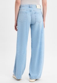 Lichtblauwe wijde jeans van denim, met een middelhoge taille, twee achterzakken en rafelige details aan de onderkant.