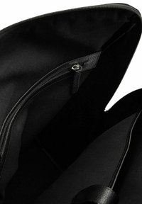 Svart tygväska inuti med ett dragkedjefack, som har en slät yta och flera fack. Enkel design, utan mönster eller dekorationer.