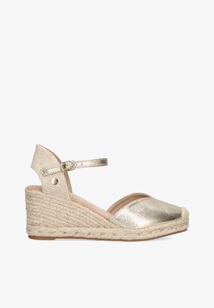 Sandalia de cuña de espadrille en metal dorado con suela de yute trenzado, tiras ajustables en el tobillo y parte superior de tela con un acabado texturizado.