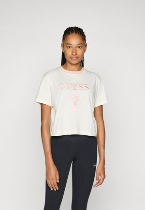Cream short-sleeve cropped t-shirt with pink collar, featuring embroidered “GUESS U.S.A.” logo and a central question mark design.