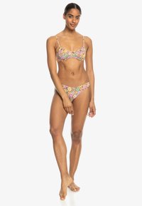 Conjunto de bikini con un patrón floral multicolor sobre un fondo claro; incluye una parte superior tipo bralette con tirantes ajustables y una parte inferior a juego.