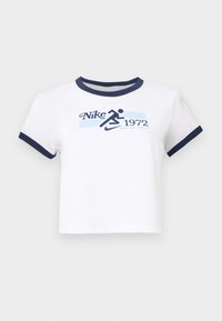 Balta kokvilnas apgriezta augšdaļa ar tumši zilu ribotu kakla izgriezumu un piedurkņu maliņām. Priekšā ir grafika ar uzrakstu "Nike 1972" un skrienošu figūru.