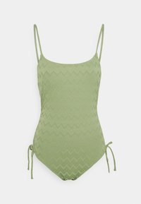 Maillot de bain une pièce vert avec de fines bretelles, présentant un motif en zigzag texturé et des liens latéraux réglables. Tissu lisse, silhouette classique.