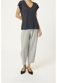 Marinblå V-hals top med korte ærmer, parret med lysegrå vide bukser og sorte spidse slingback hæle.