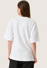 Witte katoenen t-shirt met een ontspannen pasvorm, korte mouwen en een ronde halslijn. Glad textuur met nette stiksels en een eenvoudig ontwerp.