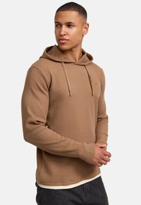 Felpa con cappuccio marrone in tessuto a coste, con tasca a marsupio frontale, cappuccio con lacci e un logo discreto sul petto.
