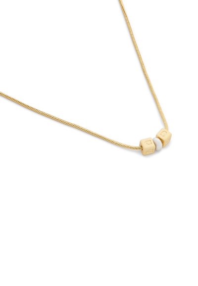 Collier chaîne en or délicat avec deux perles cubes dorées et une perle ronde blanche enfilées au centre sur un fond blanc.