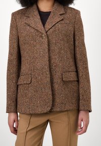 Brun herringbone-blazer i strukturerad tyg, med slagkrage, en knapp och två framfickor.