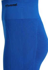 Niebieskie legginsy sportowe z prążkowaną teksturą na pasku, z wzorem w jodełkę po bokach. Logo Hummel na pasku.