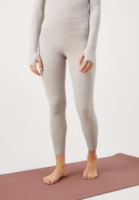 Jasnoszare dopasowane legginsy z wysokim stanem, gładką teksturą i bez widocznych wzorów, w połączeniu z pasującą bluzą z długim rękawem.