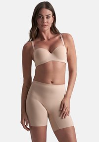 Beige naadloze bh met vormgegeven cups en dunne verstelbare bandjes, gecombineerd met hoog-taille beige shapeshorts, zachte textuur.