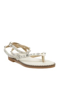 Sandalias planas blancas con un diseño de tira en T, adornadas con embellishments en plata y acentos florales, que cuentan con una cómoda plantilla beige y suela de goma.