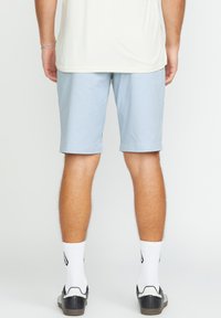 Light blue shorts made of smooth fabric, knee-length, with a straight fit. Worn with white socks and black athletic shoes.