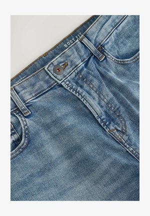 Jeans de mezclilla azul con un diseño de ajuste bota, con cierre de botones, costuras en contraste y una etiqueta en la cinturilla.