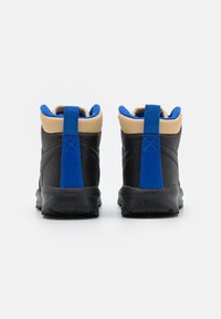 Para czarnych butów turystycznych z niebieskimi uchwytami i beżowymi wyściółkami, widocznych z tyłu na białym tle.