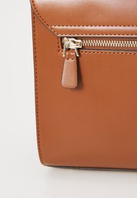 Borsa in finta pelle marrone con forma rettangolare, caratterizzata da una chiusura con zip decorata con un piccolo tirante e dettagli di cucitura in contrasto.