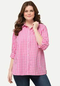 Camicia a quadri rosa con maniche lunghe arrotolate, dotata di colletto classico e orlo con spacco laterale. Materiale in cotone testurizzato.