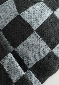 Schwarzer und grauer Strickstoff mit einem karierten Muster aus abwechselnd großen Quadraten; weiche Textur mit sichtbaren Fasern und warmer Ausstrahlung.