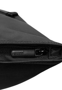 Bolsa negra hecha de material liso, con un cierre de cremallera y un tirador de marca. Diseño aerodinámico sin patrones o acentos visibles.