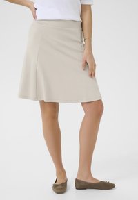 Beige utsvängd kjol i mjukt material, med en slät midja och en knälång fåll som har en mjuk drapering. Minimalistisk design, inga mönster.