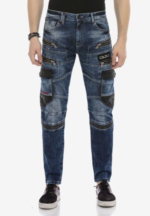 Blaue Denim-Cargo-Hosen mit mehreren Reißverschlusstaschen, schwarzen Stoffakzenten und einem distressed Finish; schmaler Schnitt mit kontrastierenden Nähten.