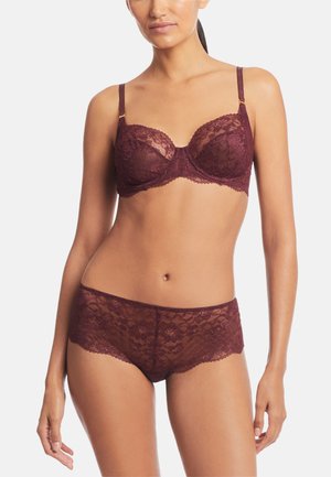 Kanten beha en bijpassende boyshort in diep bordeauxrood. Heeft ingewikkelde bloempatronen, semi-doorzichtig materiaal en verstelbare bandjes met gouden accenten.