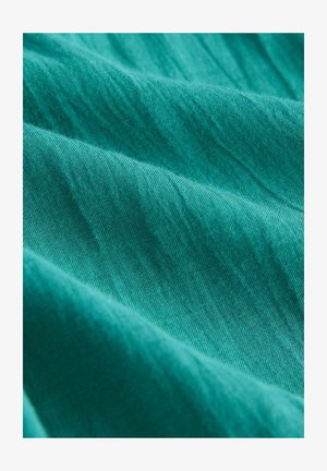 Teal kangas sujuva tekstuuriga, millel on peened lained ja värvitoonide variatsioonid, mis näitavad kerget ja hingavat kvaliteeti.