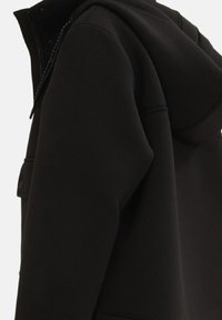 Giacca nera con cappuccio, dalla texture liscia, dotata di chiusura con zip e tasche laterali. Il design presenta una forma minimalista e sottili dettagli di cucitura.