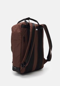 Hnědý batoh s černými akcenty, vyrobený z texturované tkaniny. Obsahuje nastavitelné popruhy, síťovou panel a boční kapsu na zip.