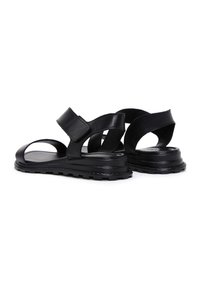 Sandali neri in pelle con design aperto sulla punta e cinturini incrociati con chiusura in velcro. Suola testurizzata per una maggiore aderenza.
