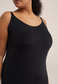 Fekete ujjatlan ruha sima, rugalmas anyagból. Kerek kivágással és testhezálló szabással rendelkezik, ami lehetővé teszi a szabad mozgást.