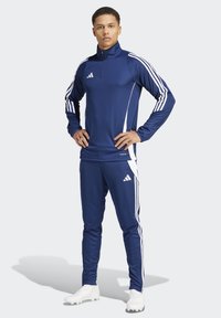 Marineblauer Sportanzug mit Stehkragen, weißen Akzenten und drei weißen Streifen an den Ärmeln und Hosen. Leichter Stoff.