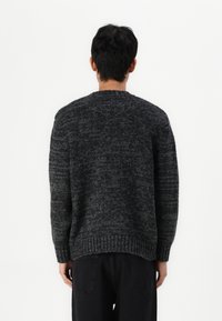 Pull en maille gris foncé avec un motif texturé, col rond et ourlet côtelé. Présente des épaules tombantes et une coupe décontractée.