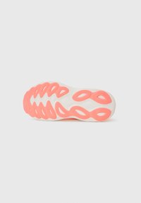 Sål av sko med hvit base og rosa detaljer, med en bølgete design og perforerte detaljer for grep og fleksibilitet.