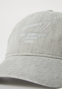 Casquette en coton gris avec une visière courbée, ornée d'un texte et d'un logo brodés en bleu clair sur le devant, et d'un motif de tissu texturé.