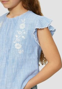 Gestreifte hellblaue Bluse mit Rüschensleeves, bestickten floralen Details in Weiß, weichem Material und lockerer Passform.