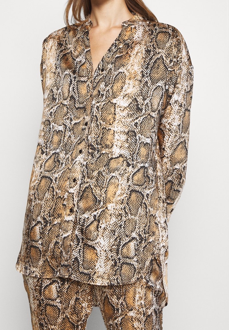 Brun och svart ormtrycksskjorta med långa ärmar, krage och knappdetalj fram. Slät, silkig textur.