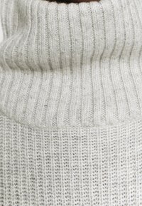 Maglione dolcevita grigio chiaro con texture a coste e design a maglia spessa. Morbido filato con un collo alto e ripiegato per garantire calore.