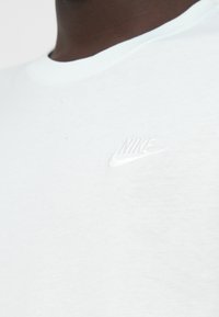 Λευκό βαμβακερό T-shirt με στρογγυλή λαιμόκοψη και ανοιχτό μπλε λεπτομέρεια. Διαθέτει διακριτικό, ανάγλυφο λευκό λογότυπο Nike στο στήθος.