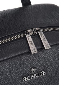 Sac à dos en cuir noir texturé avec quincaillerie à fermeture éclair en argent et détail de logo. Présente deux tirettes de fermeture éclair et un design minimaliste.