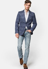 Granatowa marynarka w kratę o zorganizowanej konstrukcji, noszona na białej koszuli. W połączeniu z jasnoniebieskimi dżinsami i brązowymi butami. Teksturowany materiał.