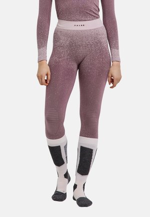 Frau trägt rosa und violett gesprenkelte Leggings und passendes Oberteil, kombiniert mit weißen und schwarzen Kniestrümpfen.