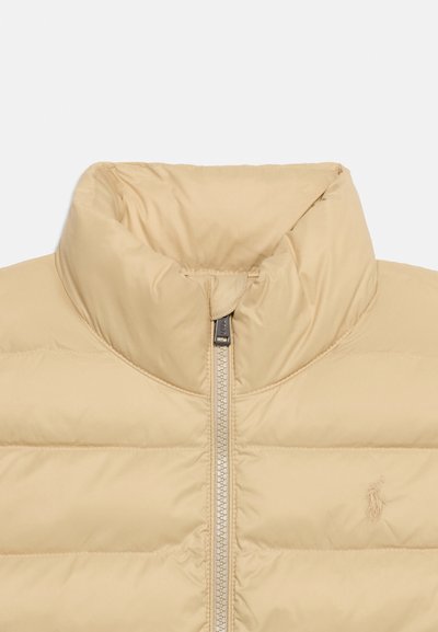 Μπεζ μπουφάν με ψηλό γιακά, ολόκληρο φερμουάρ μπροστά και λεπτό κεντημένο λογότυπο στο στήθος.