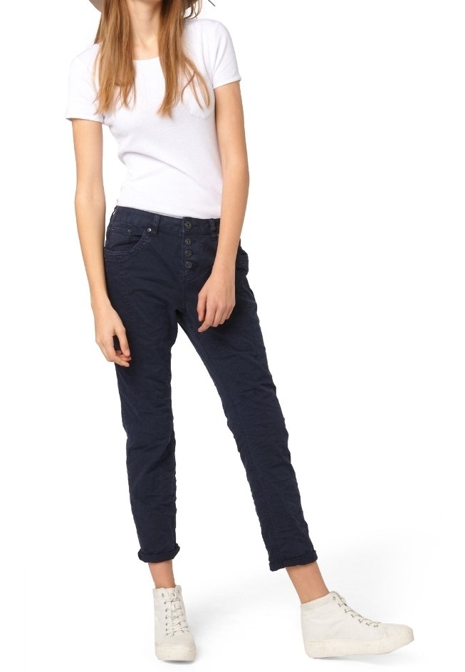 Mörkblå byxor med avsmald passform, försedda med flera knappar fram, stylade med en vit kortärmad skjorta och vita högpromenadsneakers.