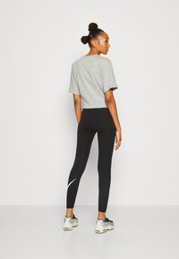 Grå kortärmad t-shirt i kombination med svarta leggings med vit accent, kompletterat med svarta och silverfärgade träningsskor.