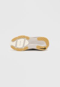 Suola di scarpa atletica con una intersuola bianca, suola in gomma marrone e beige con un motivo testurizzato per una migliore trazione.