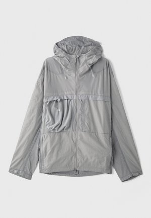 Lightweight gray jacket with a hood, zippered front, large chest pocket, textured fabric, and elastic drawstrings at the hood and hem.