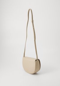 Borsa a tracolla beige con forma arrotondata, texture in pelle liscia, tracolla regolabile e design minimalista. Nessun dettaglio hardware visibile.