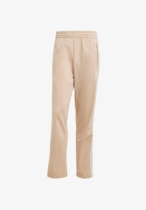 Pantaloni sportivi beige con una texture liscia, fascia elastica in vita, tasche laterali e strisce laterali bianche. Presenta un dettagli del logo sul davanti.